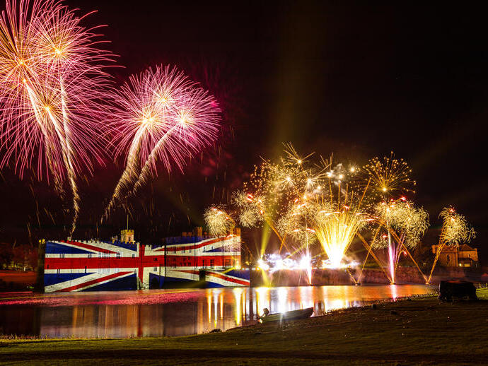 Feuerwerk und eine große Union-Jack-Beleuchtung auf einer Burgmauer bei Nacht