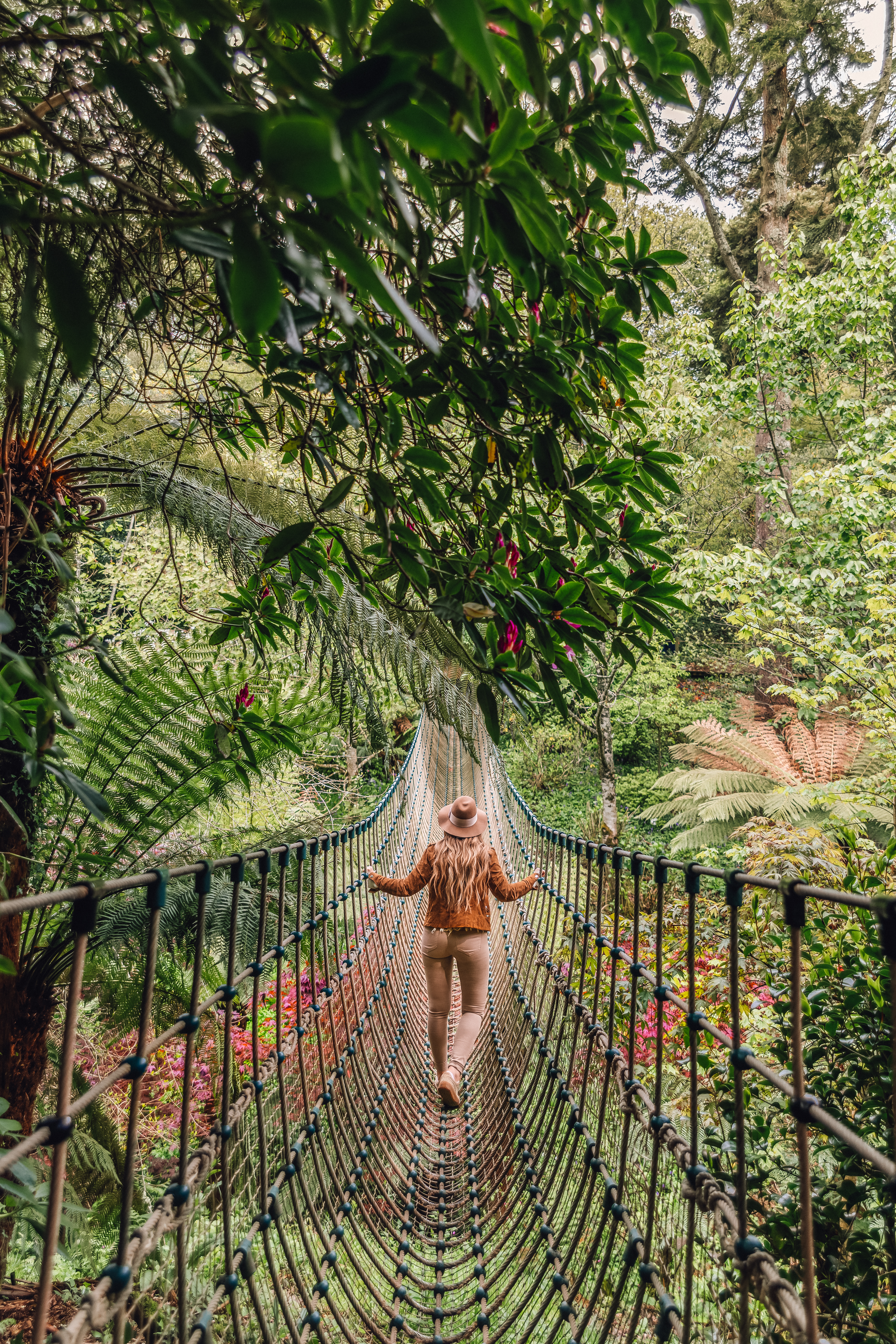 Woman walking across a rope bridge surrounded by trees