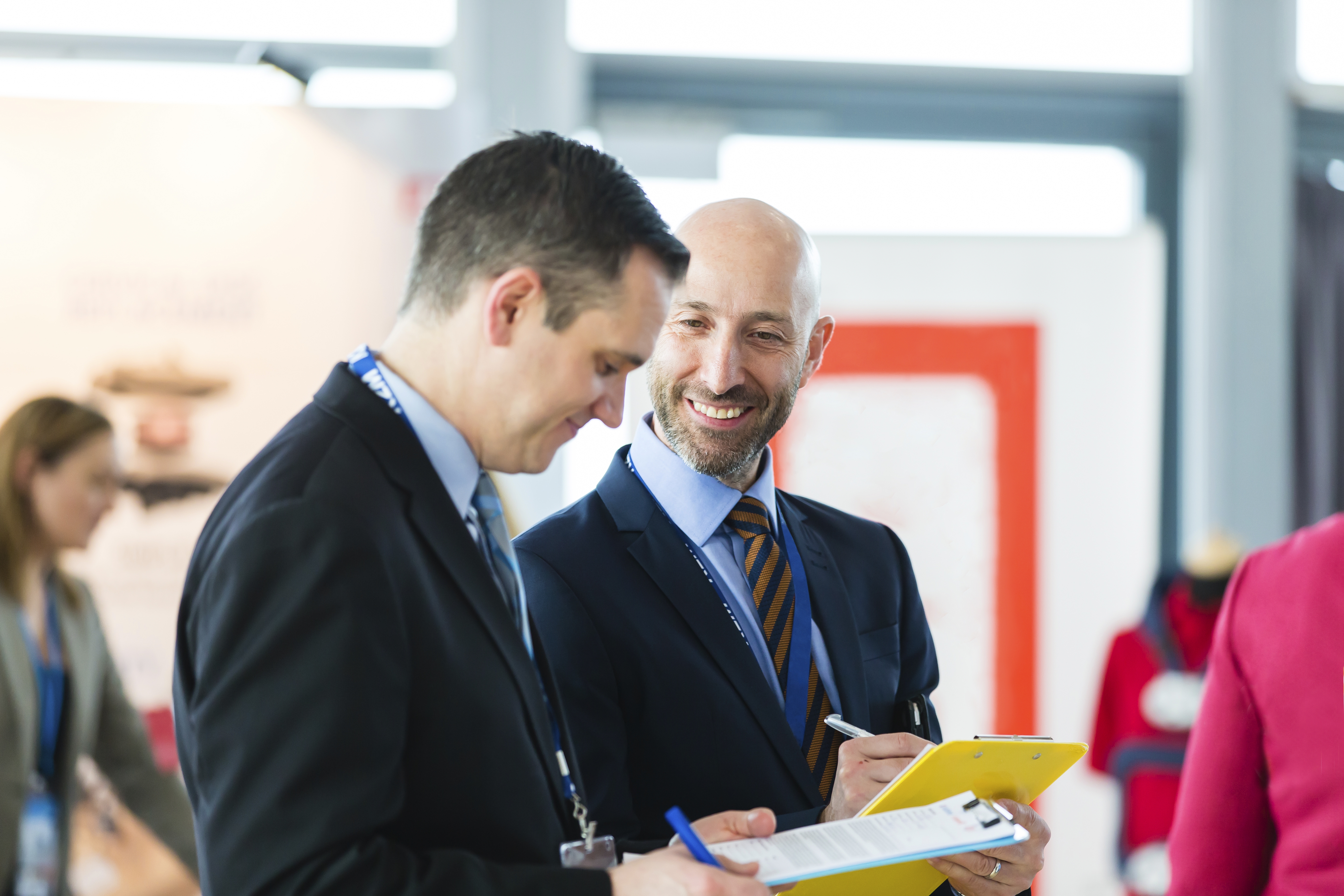 Two men in formal attire, filling out forms