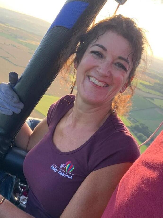 Una donna sorridente in una mongolfiera con i campi sottostanti