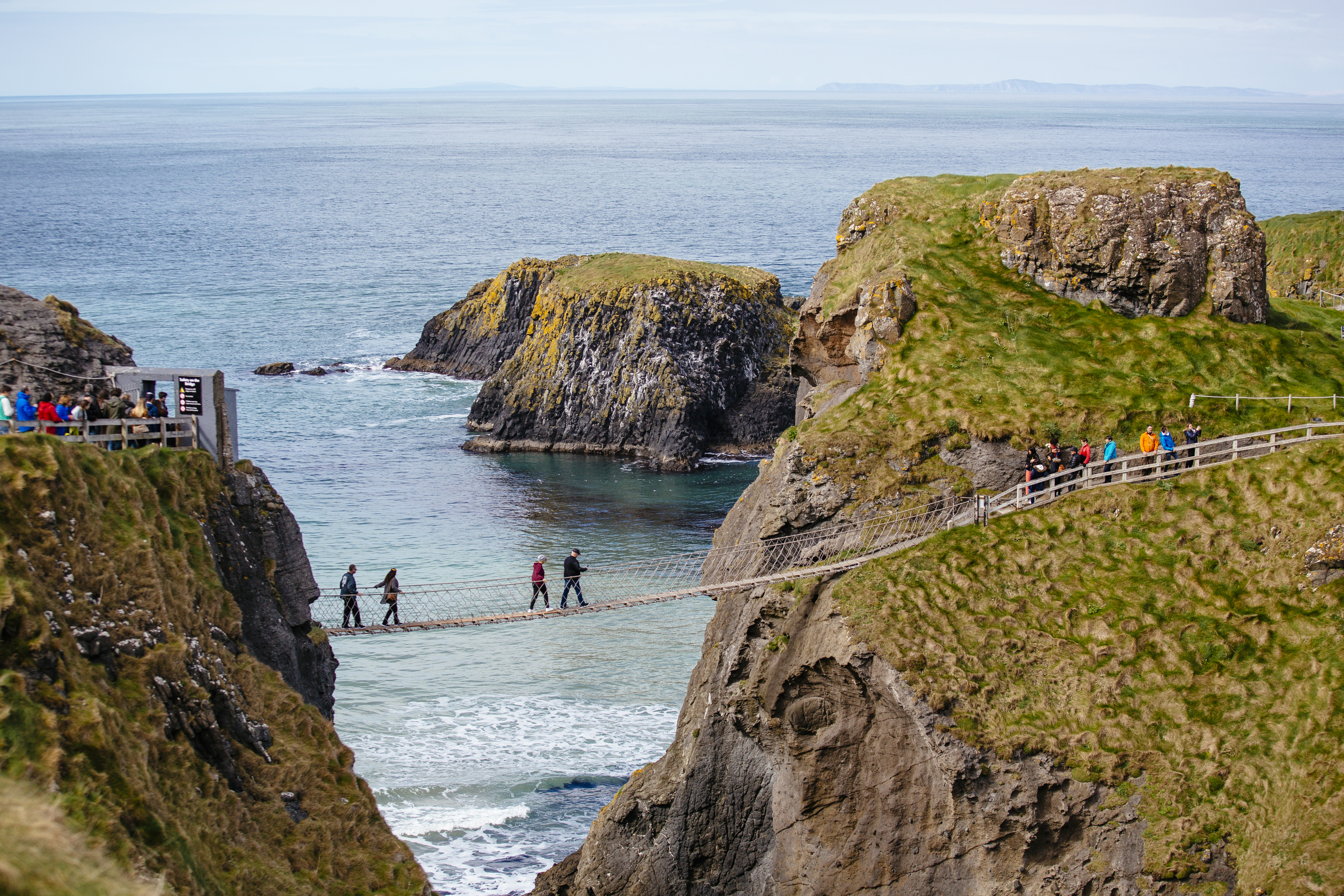 People crossing a rope bridge over the sea