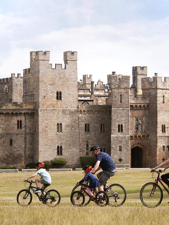 Family cycling past castle in North East England