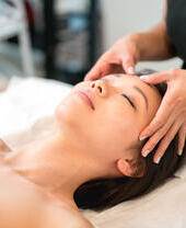 Una mujer recibiendo un masaje facial en el spa de un hotel.