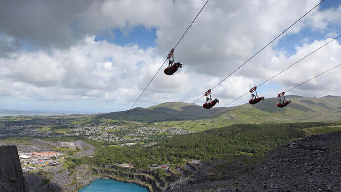 Persone che attraversano una grande cava con una teleferica.