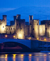 A castle lit up at night by the river
