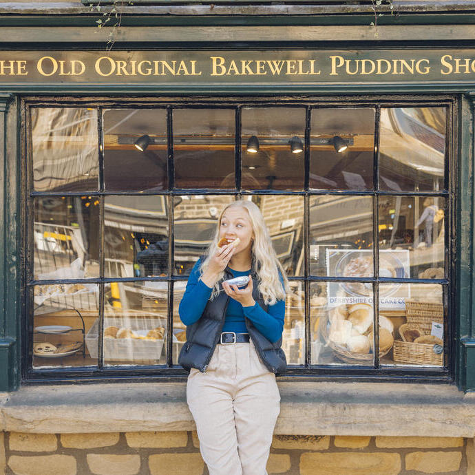 Frau, die vor einer Bäckerei eine Bakewell-Torte isst