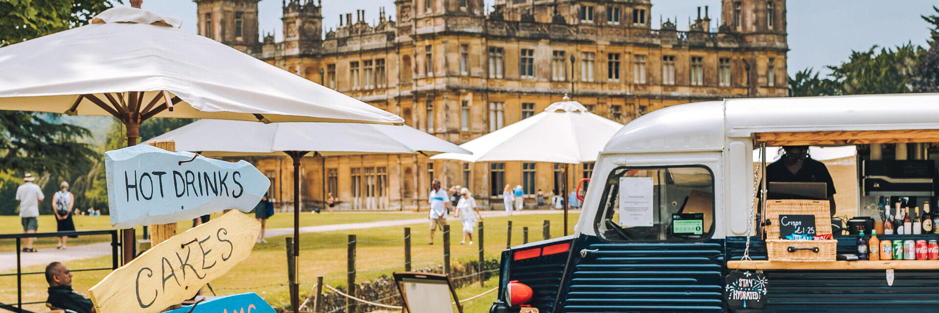 Un food truck, des parasols et des panneaux indicateurs dans l'enceinte d'un château