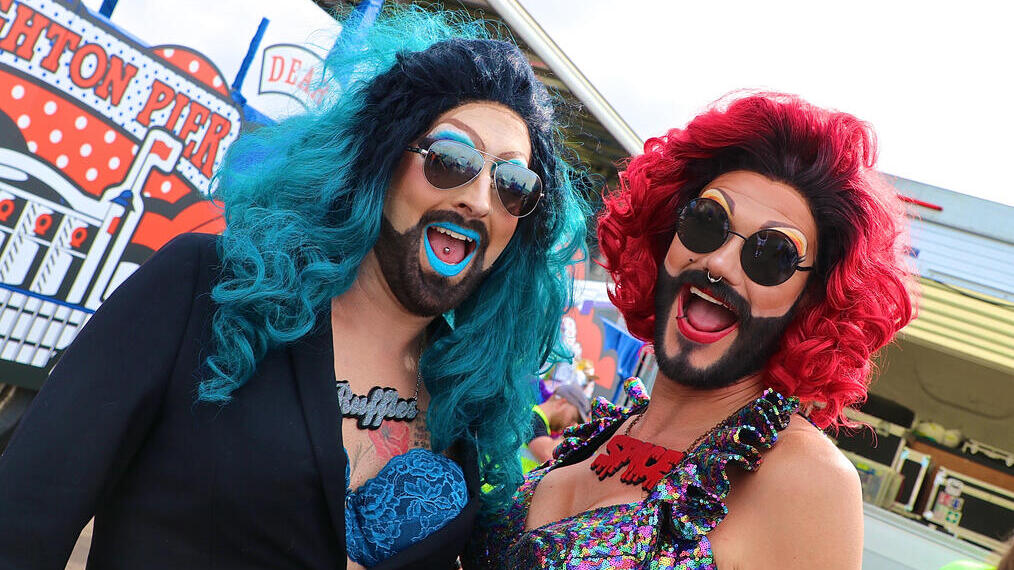 Two persons in drag costumes smiling towards camera