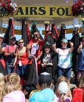 Crowd looking at people posing under a bandstand, with a banner reading: Broadstairs Folk Week