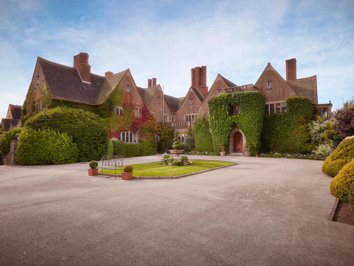 La entrada principal, el camino de acceso y los cuidados jardines de un hotel y spa rural.