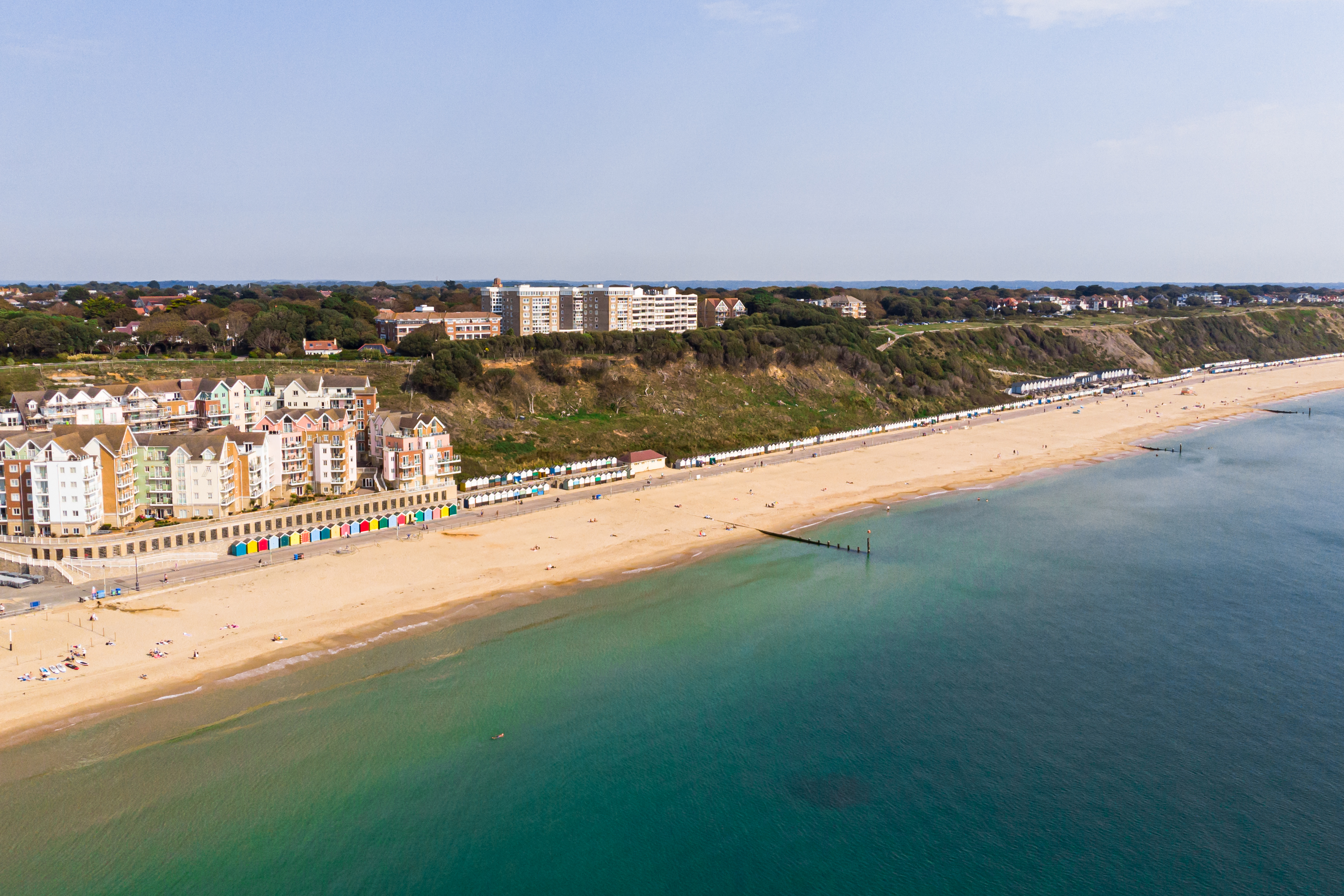 Ripresa aerea di una spiaggia sabbiosa con cabine colorate.