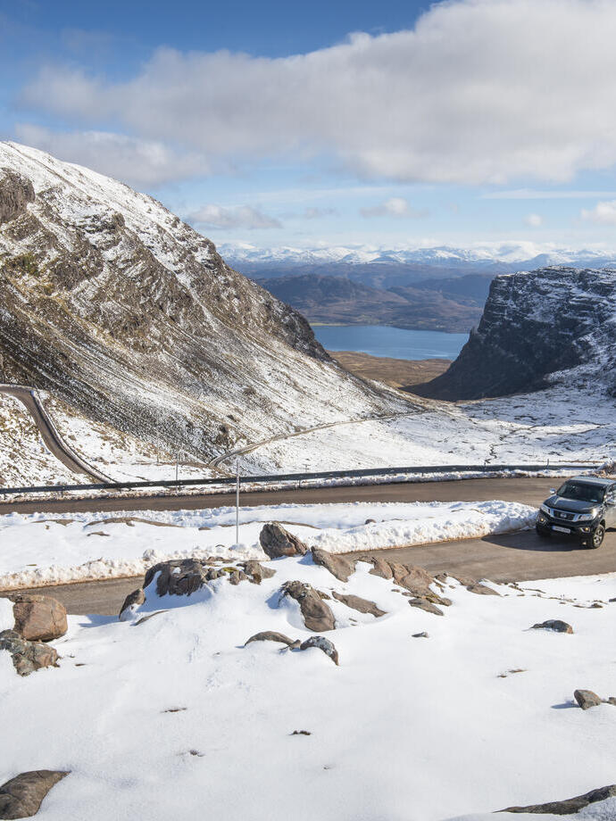 A car on a mountain road surrounded by snow