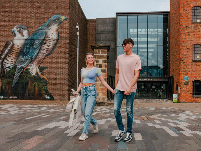 A couple walking past street art outside a museum