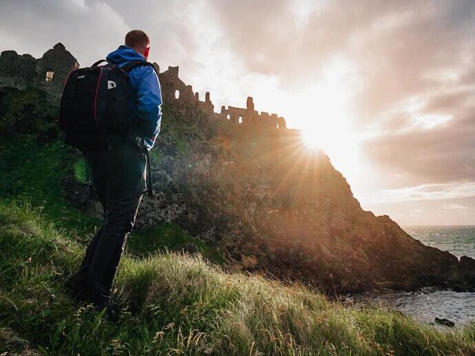 Homme marchant sur une colline au coucher du soleil