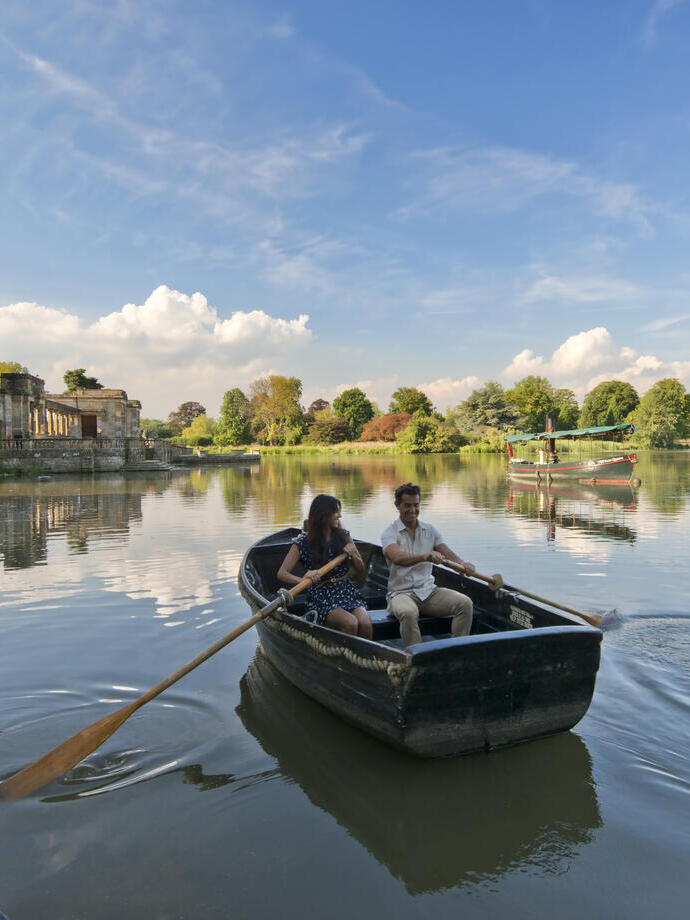 A man and woman in a rowing boat, rowing in still waters