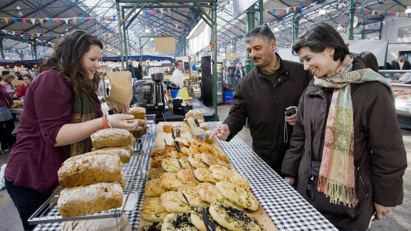 People looking at baked goods at indoor market