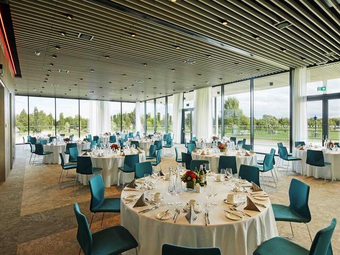 A number of round dining tables are laid with white table clothes and set for a meal
