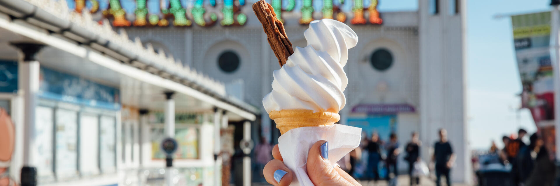 Close up of person holding ice cream cone on pier