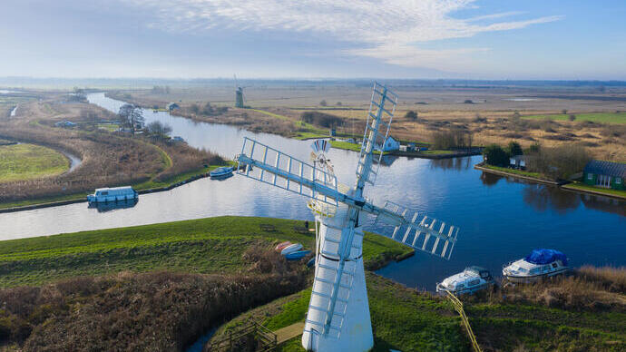 Aerial view of a windmill and surrounding pasture and canals