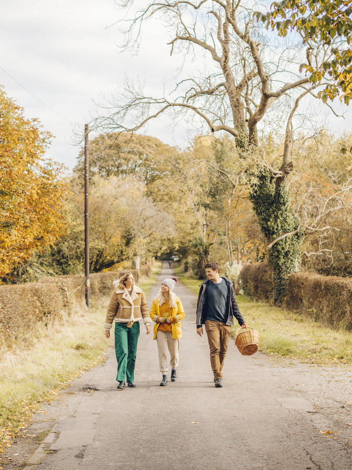 Due donne e un uomo che camminano su una stradina di campagna in autunno