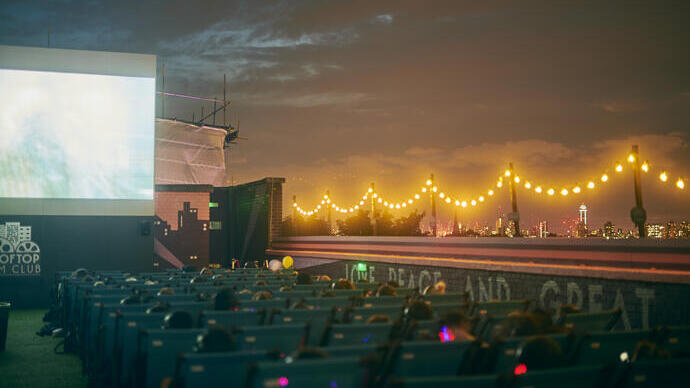 People watching a movie on a large screen at night with the city skyline in the distance