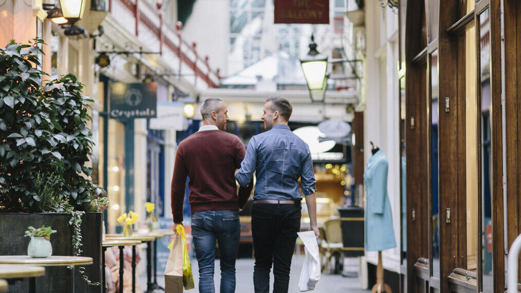 Ein schwules Paar, Arm in Arm, beim Einkaufen in einem Geschäft