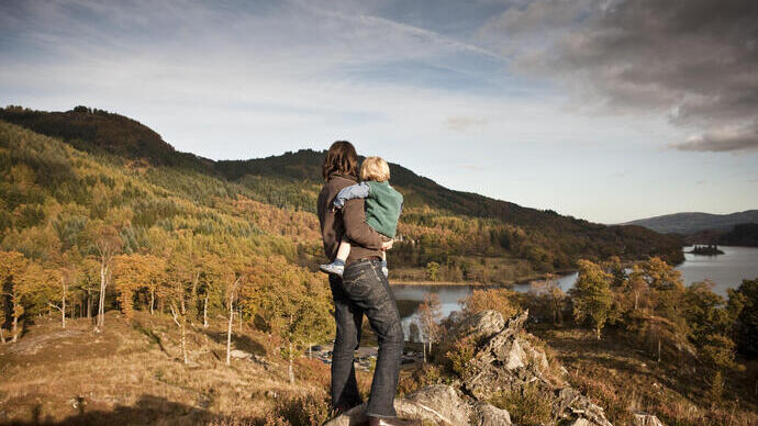 Woman and child standing on a hilltop overlooking a lake.