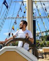 Un hombre de pie junto al timón de un barco en el puerto de Bristol.