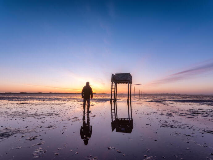 Posts marking the pilgrims' way crossing to Lindisfarne with emergency refuge at sunrise
