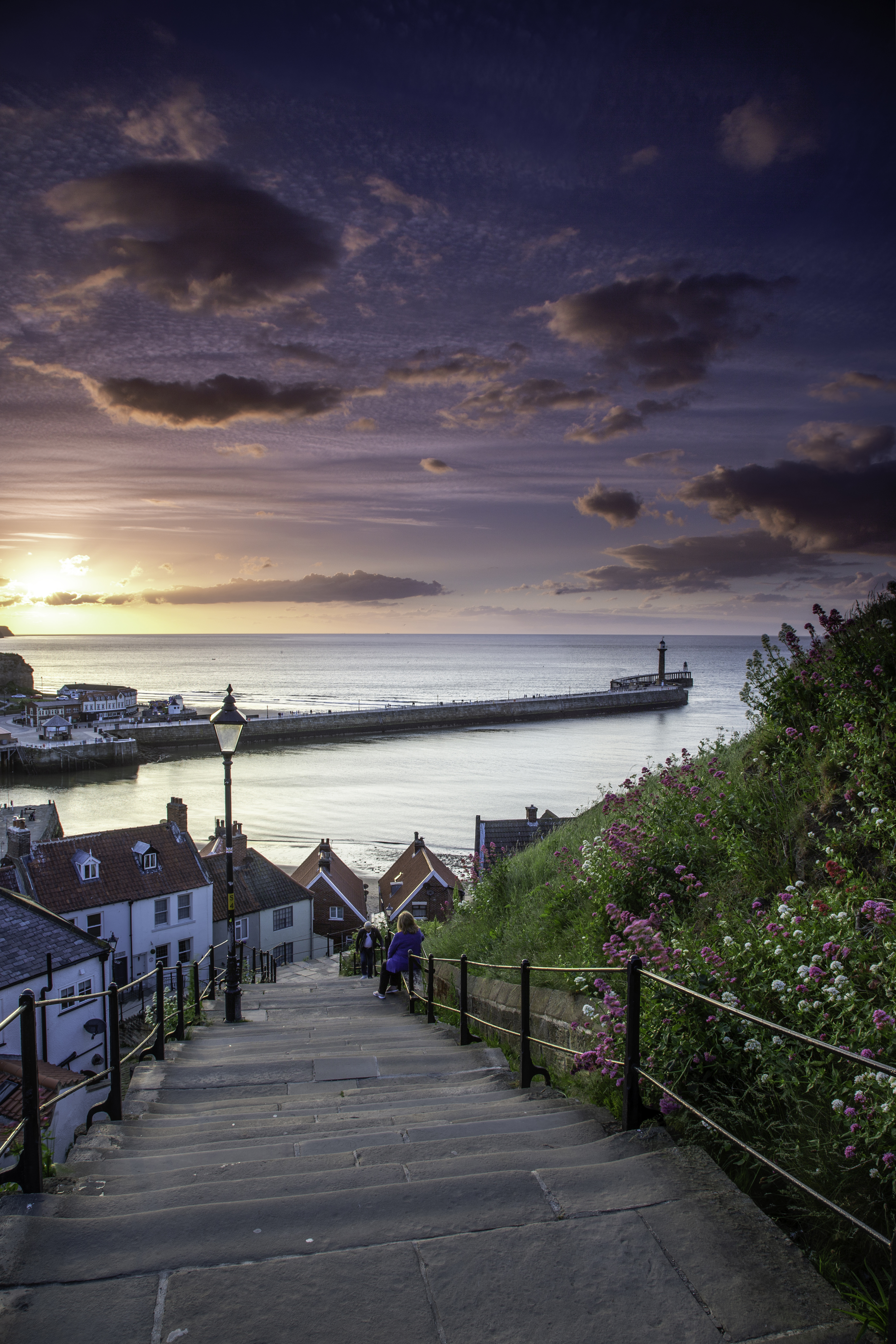 Two people on the steps of a cliff by the sea
