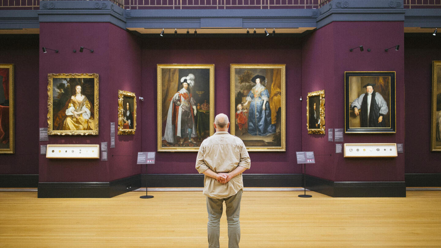 Vue de dos d'un homme debout regardant des portraits dans une galerie