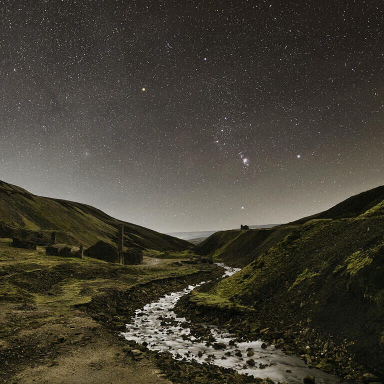 A stream winding through the mountains under a starry sky.