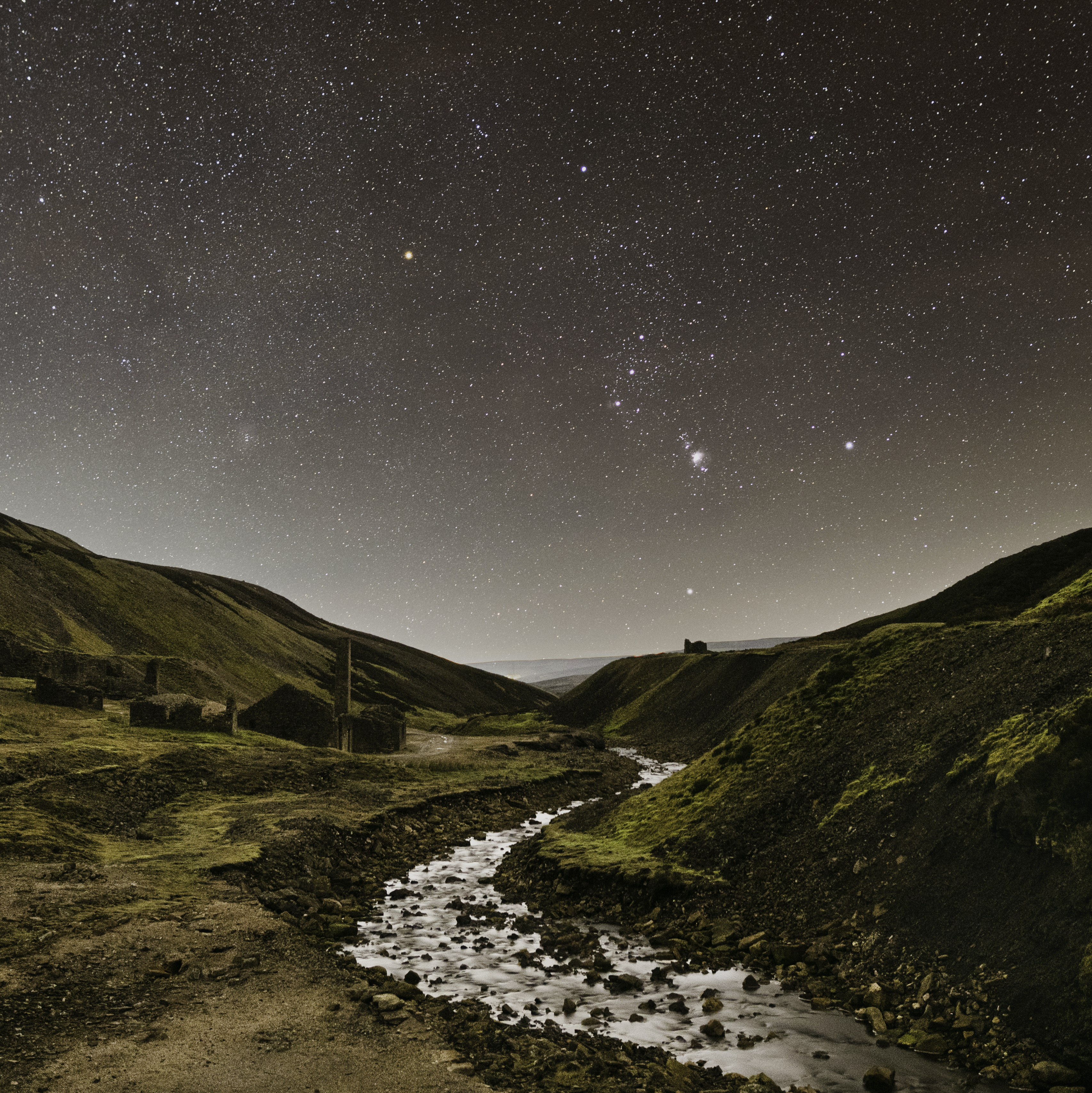 A stream winding through the mountains under a starry sky.