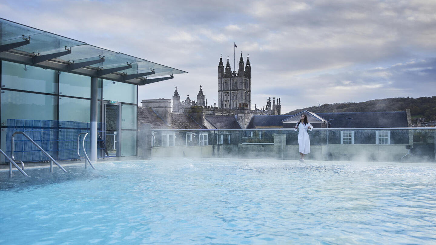 Frau in einem weißen Gewand, die neben einem Dachpool steht