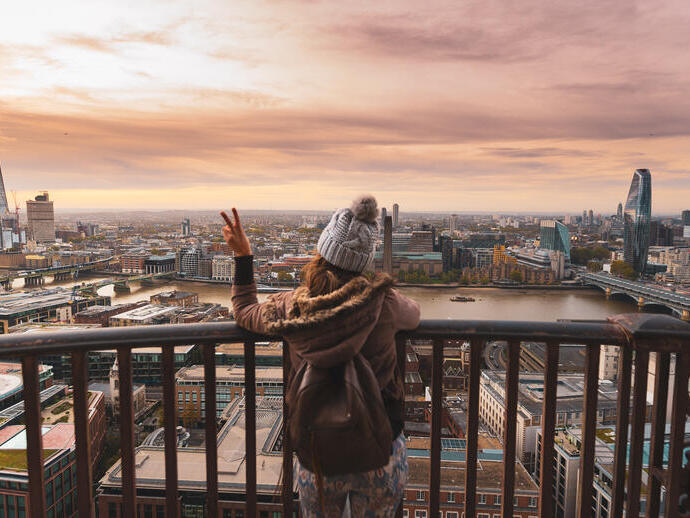 Donna su un balcone in cima a un edificio alto che guarda la città