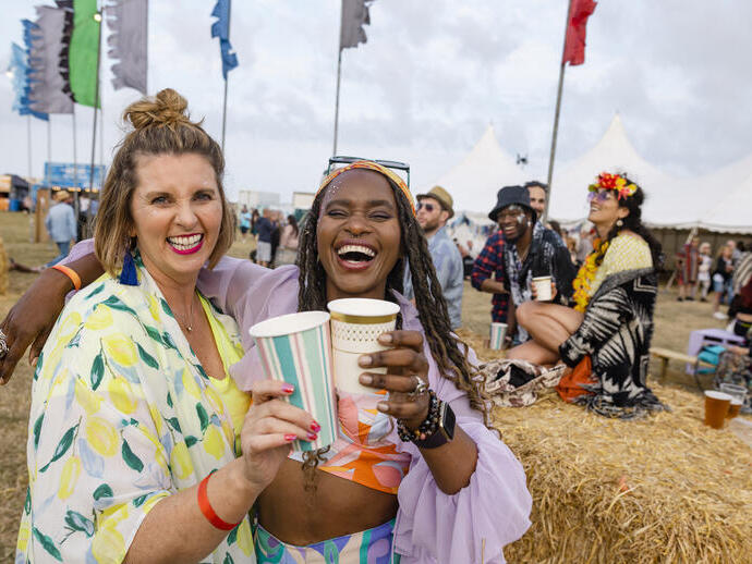Zwei Frauen, die sich mit Freunden auf einem Festival amüsieren.