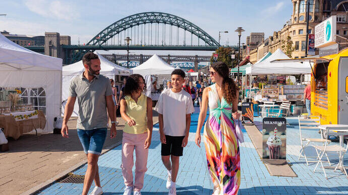 Family walking through stalls at a market in a city