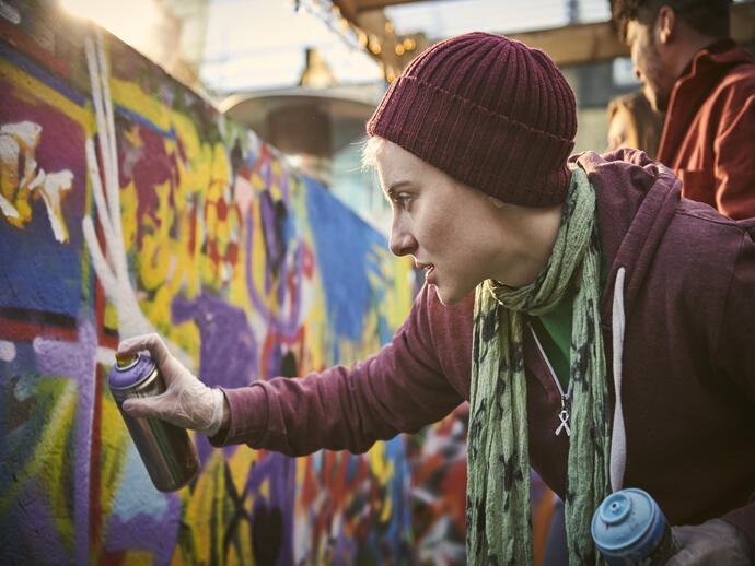 Woman using a can of spray paint to create a street art mural
