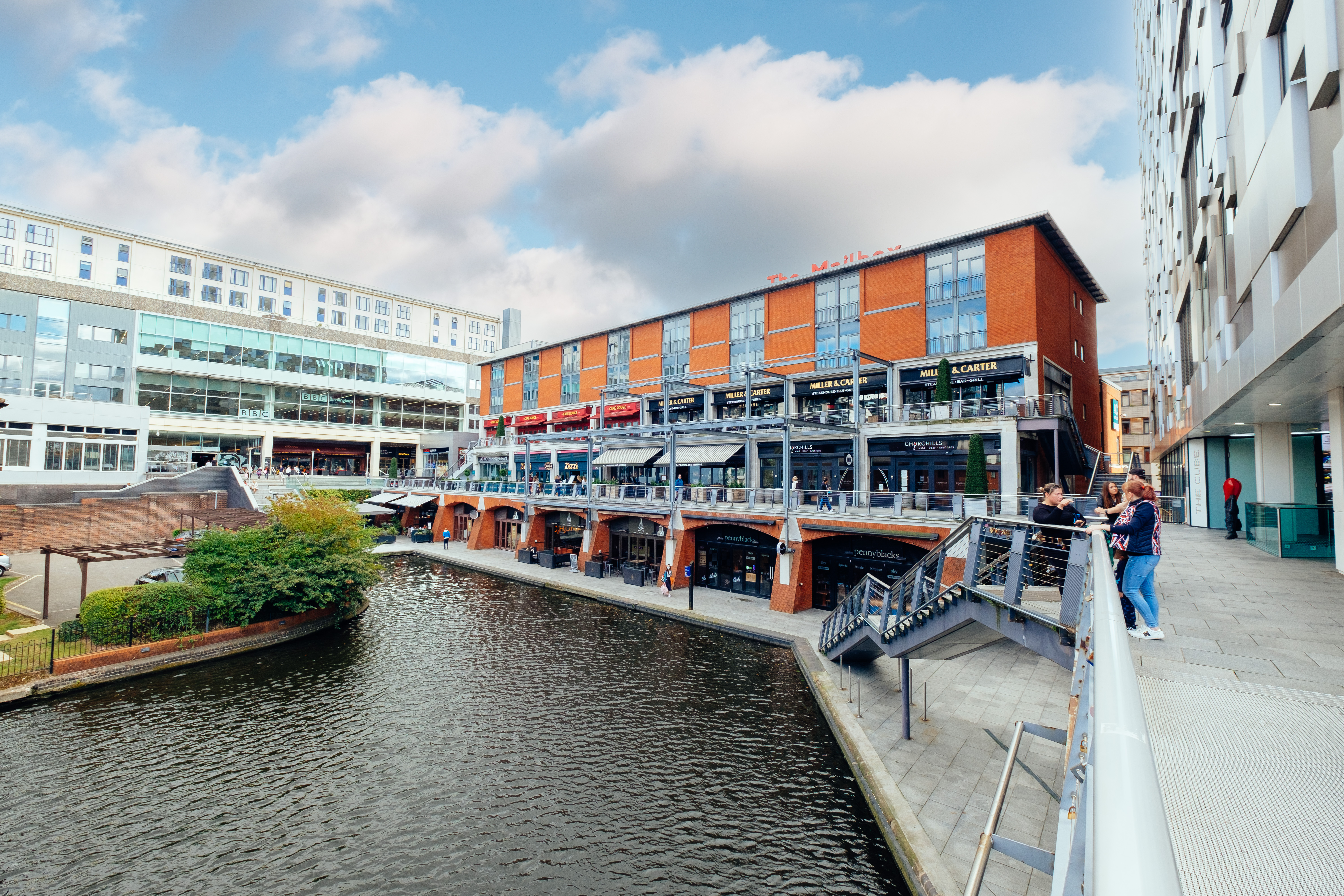 Red brick building next to tall office building beside canal