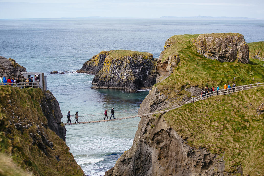 People crossing a rope bridge over the sea