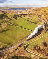 Steam train travelling along tracks in the countryside