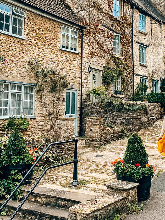 A woman in a hat walks down a street in a quaint village