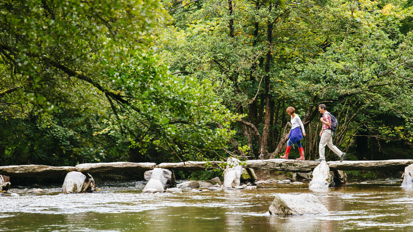 Un hombre y una mujer cruzando el río por un puente de tablas