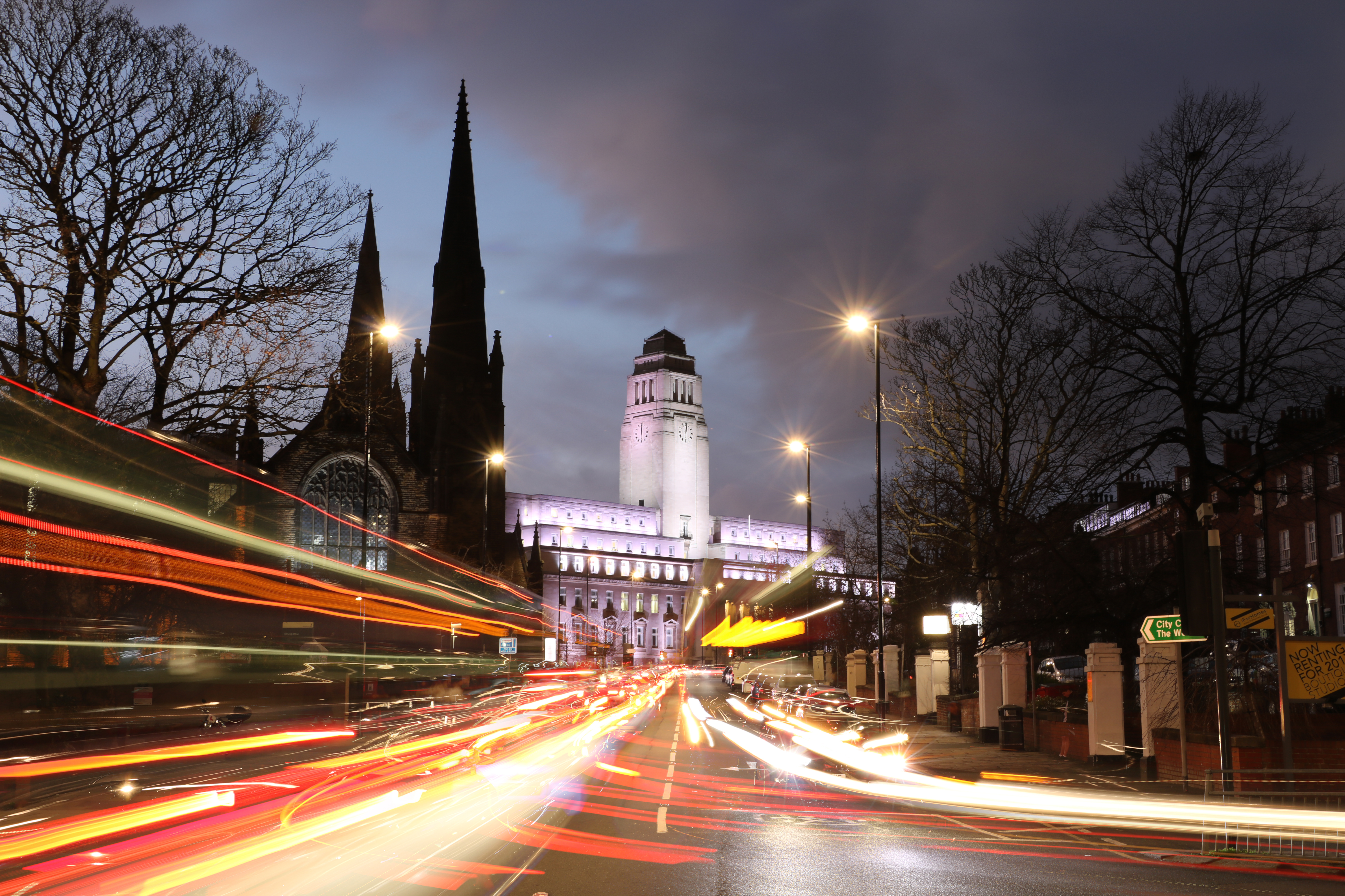 A view of a university taken from the street at night.