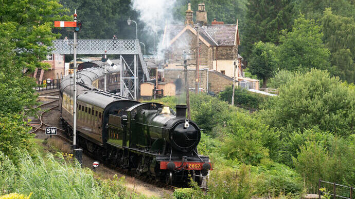 Locomotive 2857 pulling a series of carriages leaving the heritage station