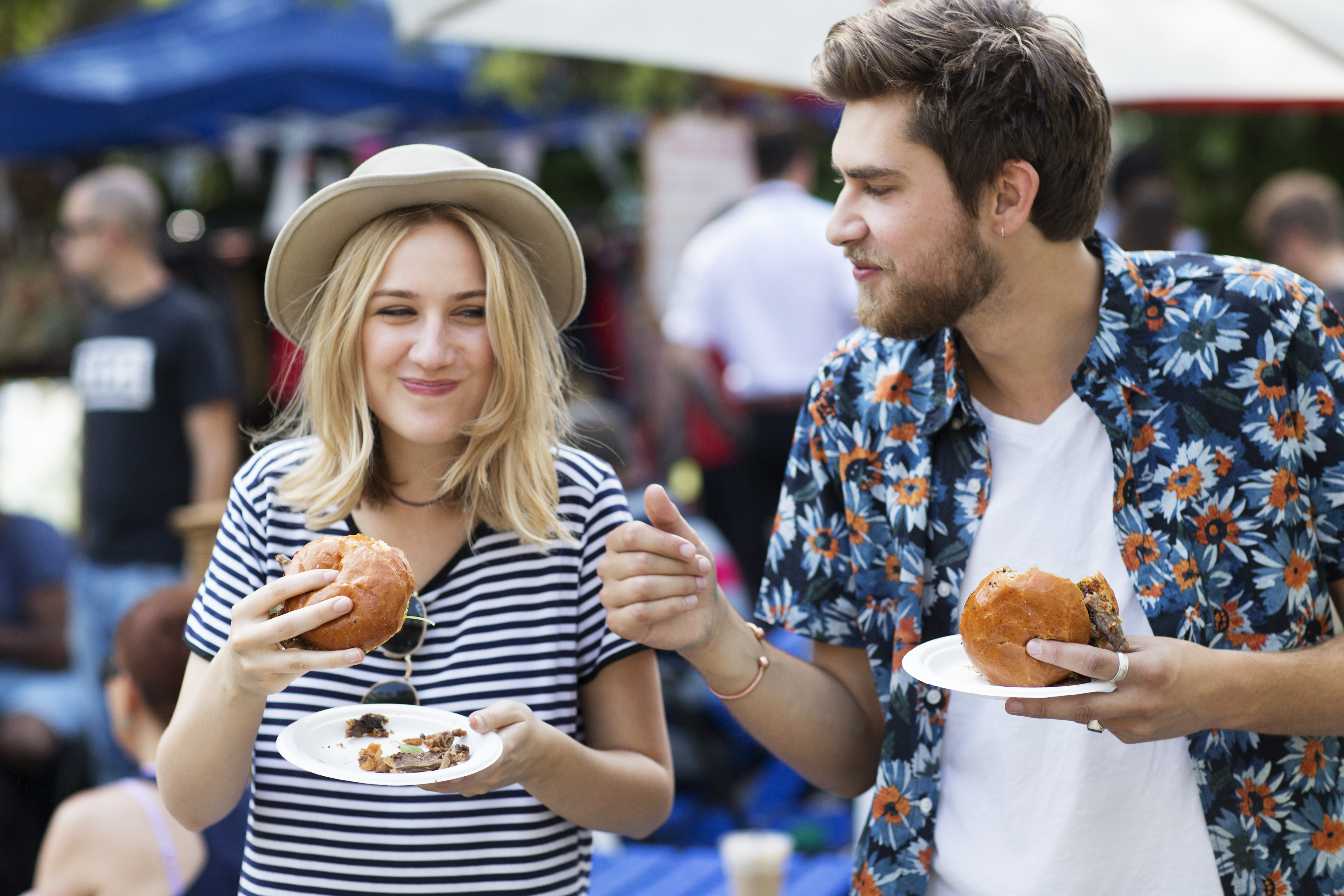 Un homme et une femme dégustent de la cuisine de rue dans un marché.