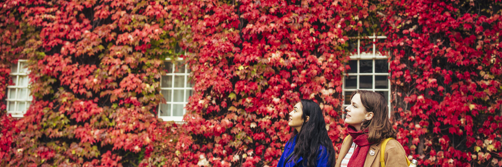 Two women in front of ivy covered wal