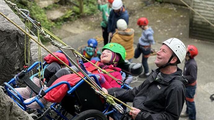 A girl in a wheelchair and a man abseil at an accessible outdoor activity centre
