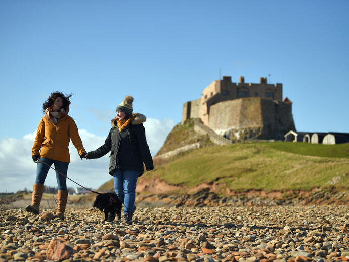 Visitors walking with their dog at Lindisfarne Castle, Northumberland