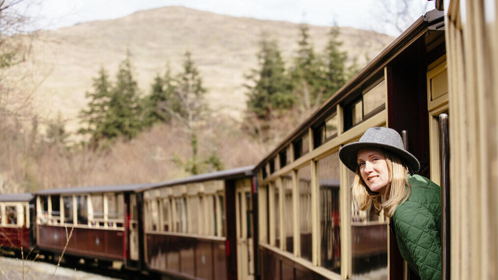 Mujer asomada a la ventana de un tren de vapor